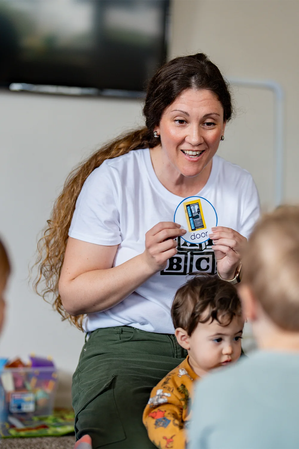 Amy Paden, plAyBCs owner, sits in a circle with children using flashcards